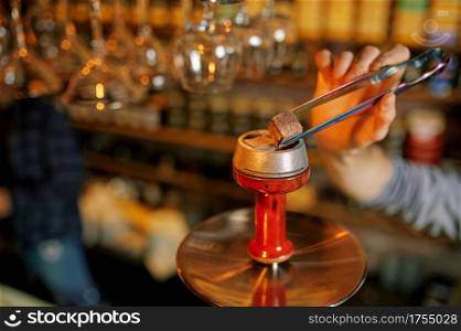 Male hookah maker, coal preparation in bar. Shisha smoking, traditional smoke culture, tobacco aroma for relaxation, rest with bong. Male hookah maker, coal preparation in bar