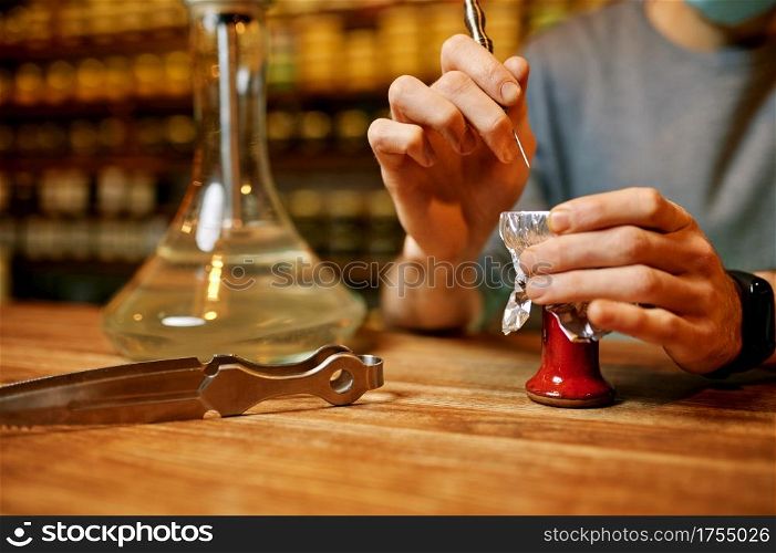 Male hookah maker, smoking preparation in bar. Shisha smoking, traditional smoke culture, tobacco aroma for relaxation, rest with bong. Male hookah maker, smoking preparation in bar