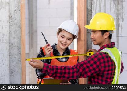 Male industrial builder workers installation process measuring wooden door with measure tape and service woman checking in building construction site. Worker work Building house concept