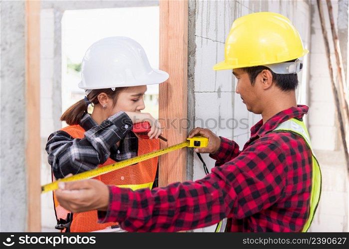 Male industrial builder workers installation process measuring wooden door with measure tape and service woman checking in building construction site. Worker work Building house concept