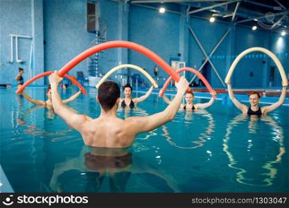 Male instructor and female group, aqua aerobics training in the pool. Man and women in the water, sport swimming fitness workout. Instructor and female group, training in the pool