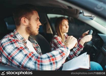 Male instructor and female student in vehicle, driving lesson, car school concept. Test for beginner. Male instructor and female student, driving lesson