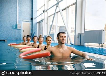 Male instructor and female swimmers group, aqua aerobics training in the pool. Man and women in the water, sport swimming fitness workout. Instructor and swimmers group, training in pool