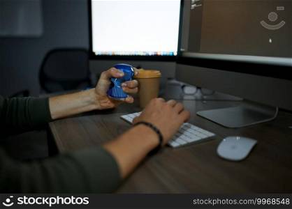 Male internet hacker eats at monitor in dark office. Illegal web programmer at workplace, criminal occupation. Data hacking, cyber security. Male hacker eats at monitor in dark office