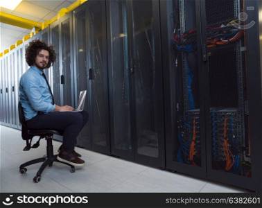 Male IT engineer working on a laptop in server room at modern data center