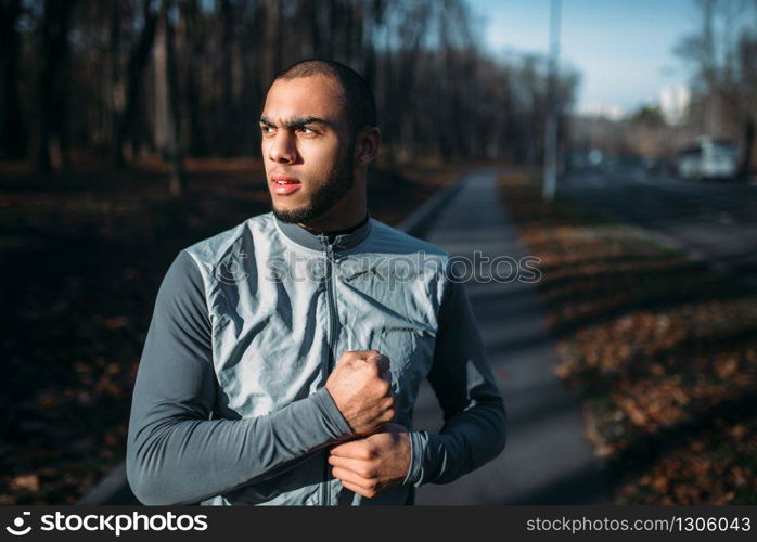 Male jogger in motion on workout outdoors. Runner in sportswear on training in park. Jogging or running