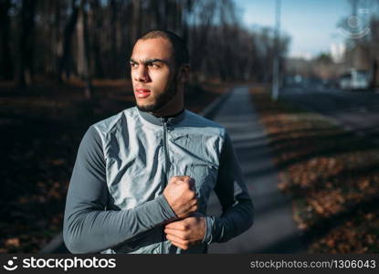 Male jogger in motion on workout outdoors. Runner in sportswear on training in park. Jogging or running