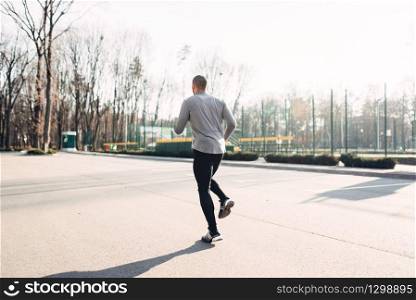 Male jogger in motion, running in autumn park, healthy lifestyle. Athlete on morning fitness workout. Runner in sportswear on training outdoor. Jogger in motion, running in autumn park