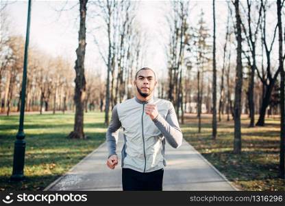 Male jogger in motion, running in autumn park, healthy lifestyle. Athlete on morning fitness workout. Runner in sportswear on training outdoor