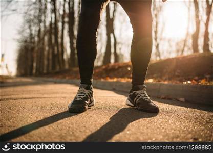 Male jogger legs, morning workout outdoors. Runner in sportswear on training in park