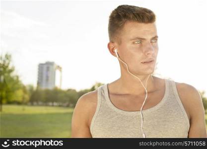 Male jogger looking away while listening music in park