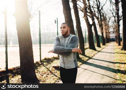 Male jogger on fitness workout in autumn park. Runner in sportswear on training outdoor. Sportsman warming up before run. Male jogger on fitness workout in autumn park