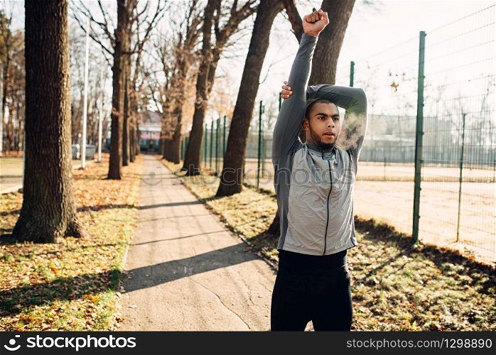 Male jogger on fitness workout in autumn park. Runner in sportswear on training outdoor. Sportsman warming up before run. Male jogger on fitness workout in autumn park