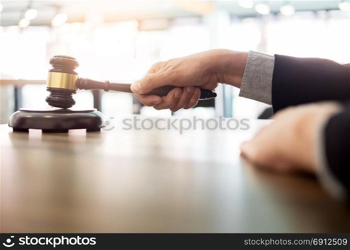 Male Judge lawyer In A Courtroom Striking The Gavel on sounding block in his office.