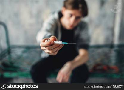 Male junkie reaching out hand with syringe. Drug addiction concept, addicted people. Male junkie reaching out hand with syringe