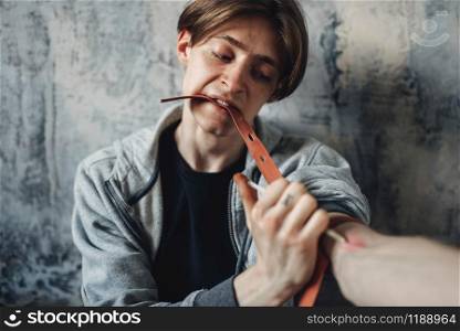 Male junkie with a syringe doing an injection dose in the arm. Narcotic addiction concept, drug addicted people. Male junkie with syringe doing an injection dose