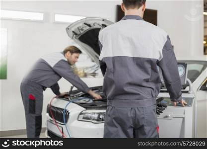 Male maintenance engineers examining car in workshop