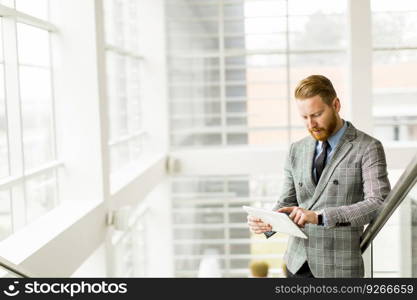 Male managing director dressed in luxury corporate clothes working on digital tablet during break