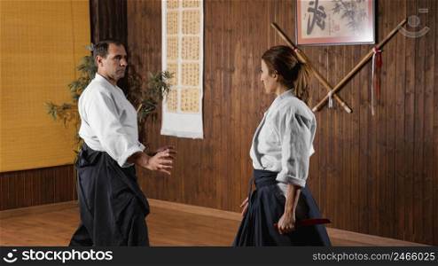 male martial arts instructor practice hall exercising with female trainee