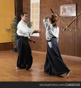 male martial arts instructor training practice hall with female trainee
