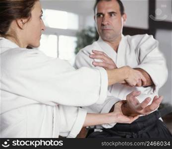 male martial arts instructor training with female trainee practice hall