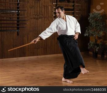 male martial arts instructor with wooden stick practice hall