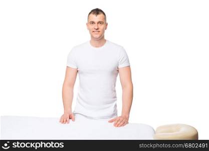 male masseur is waiting for a patient near a massage table in isolation