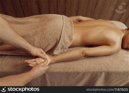 Male masseur pampering hands to young woman in towel, professional massage. Massaging and relaxation, body and skin care. Attractive lady in the spa salon. Male masseur pampering hands to young woman