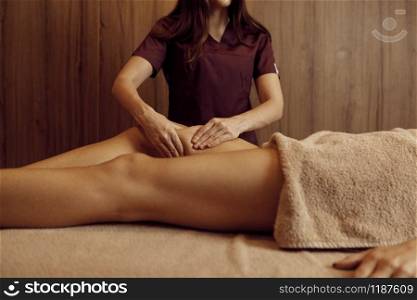 Male masseur pampering legs to young woman in towel, closeup view, professional massage. Massaging and relaxation therapy, body and skin care. Attractive lady in the spa salon. Masseur pampering legs to woman, closeup view
