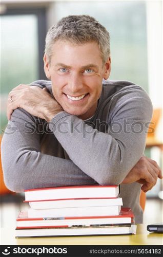 Male Mature Student Studying In Classroom With Books
