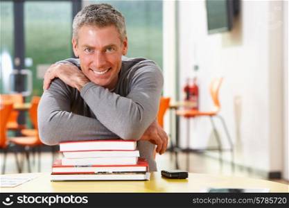 Male Mature Student Studying In Classroom With Books