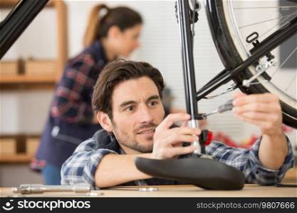 male mechanic adjusting height of bicycle saddle