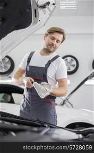 Male mechanic checking oil in car workshop
