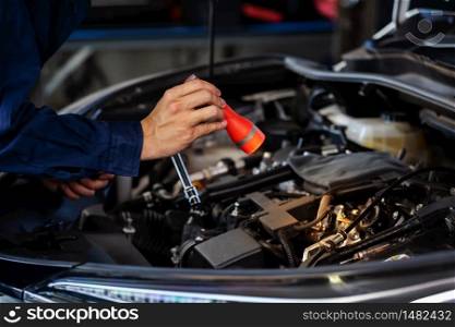 male mechanic holding and shining flashlight to checking a car engine problem