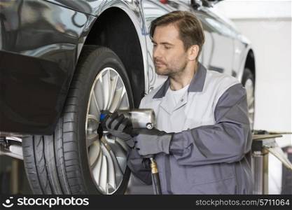 Male mechanic repairing car&rsquo;s wheel in workshop