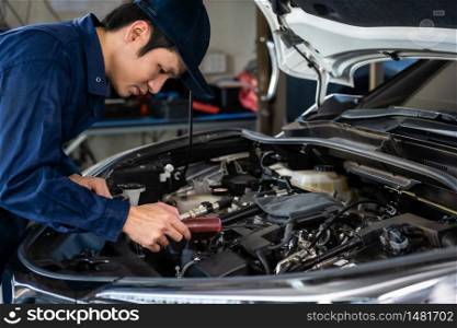 male mechanic using Tachometer checking engine of a car
