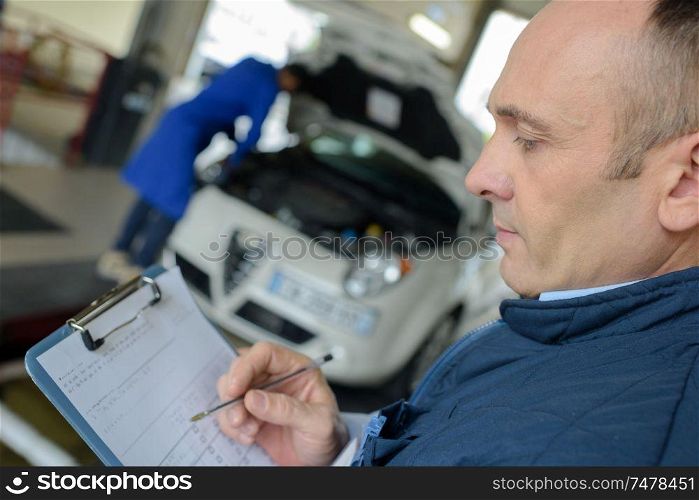 male mechanic with clipboard in garage