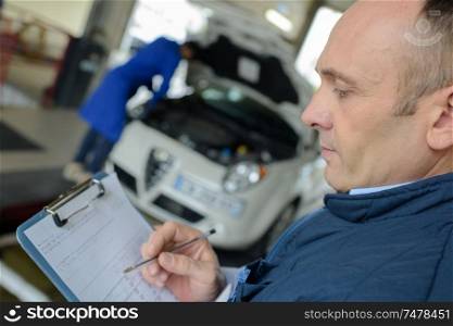 male mechanic with clipboard in garage