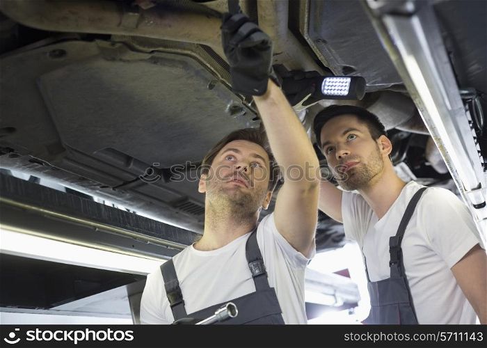 Male mechanics examining car in workshop