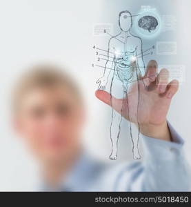 Male medical doctor working with virtual interface examining human male body