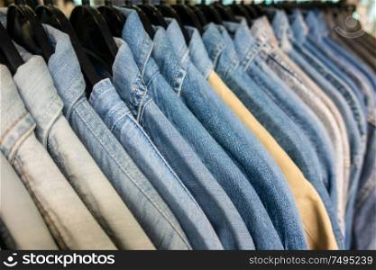 Male mens denim jeans shirts sorted on clothes hangers on a shop wardrobe closet rail