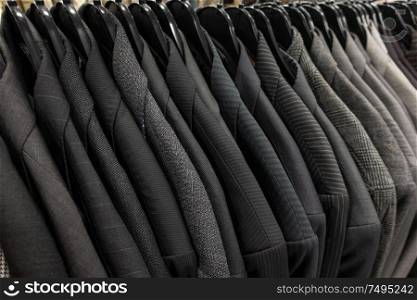 Male mens gray business suits on hangers on a shop, wardrobe or closet rail