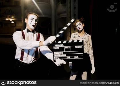 male mime artist holding clapperboard front female mime artist