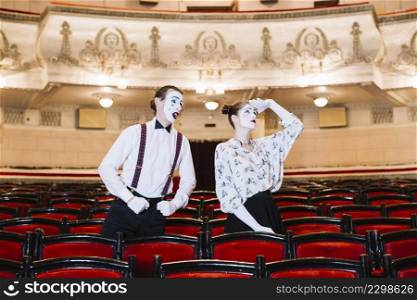male mime looking female mime looking up auditorium