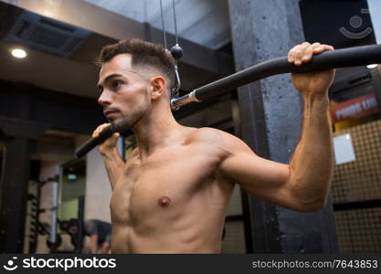 male model pulling up on horizontal bar in a gym