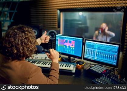 Male musician and female performer, recording studio interior on background. Synthesizer and audio mixer, musician workplace, creative process. Musician and female performer, recording studio