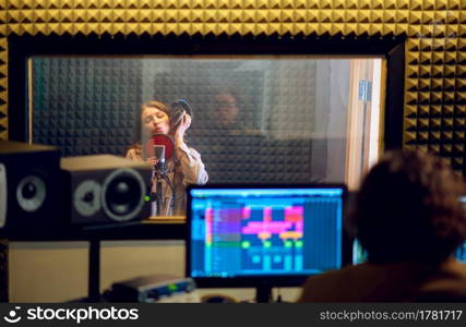 Male musician and female singer, recording studio interior on background. Synthesizer and audio mixer, musician workplace, creative process. Male musician and female singer, recording studio