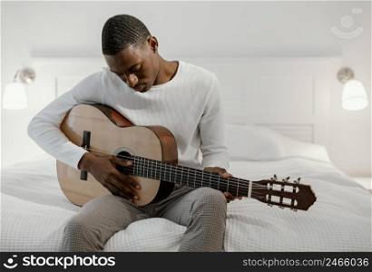 male musician bed playing guitar