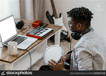 male musician home playing drums mixing with laptop