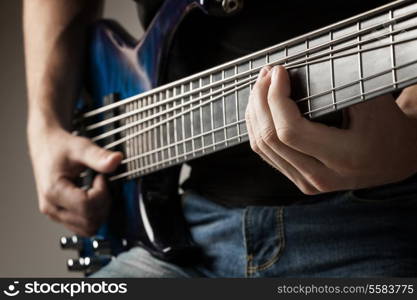 male musician playing on six-string bass guitar